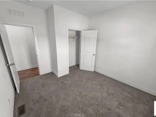 A bedroom with a carpeted floor and two doors.