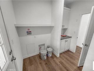 A white room with wood floors and a white door.