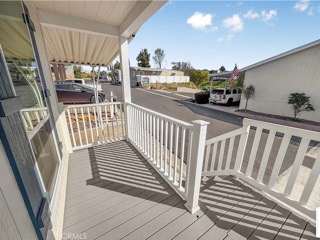 A balcony with a white railing and a view of a street with cars.