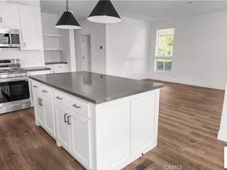 A kitchen with white cabinets and a black island.
