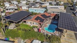 A house with solar panels on the roof and a pool in the backyard.