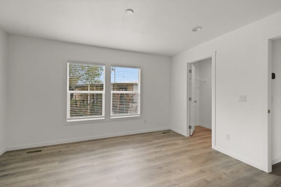 the living room of an apartment with a large window and wood flooring