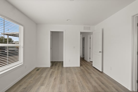 a living room with white walls and wooden floors and a large window