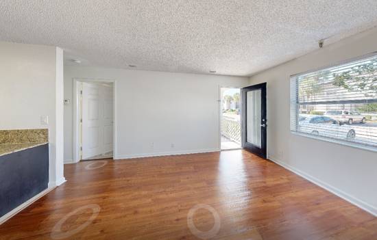 A spacious room with wooden floors and white walls.