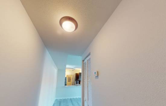 A white hallway with a light on the ceiling.