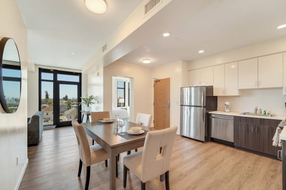 a dining room with a wooden table and chairs and a kitchen with stainless steel appliances