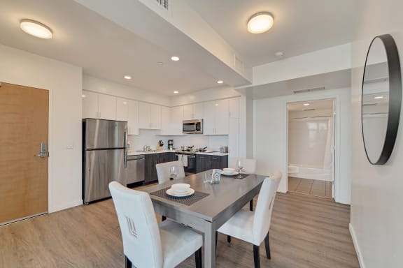 a dining area with a table and chairs and a kitchen with stainless steel appliances