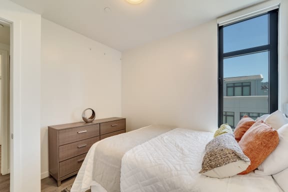 a bedroom with a large window and a bed with pillows