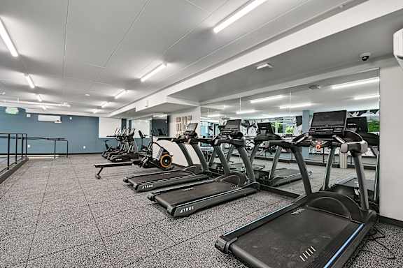 A gym with treadmills and a grey wall.