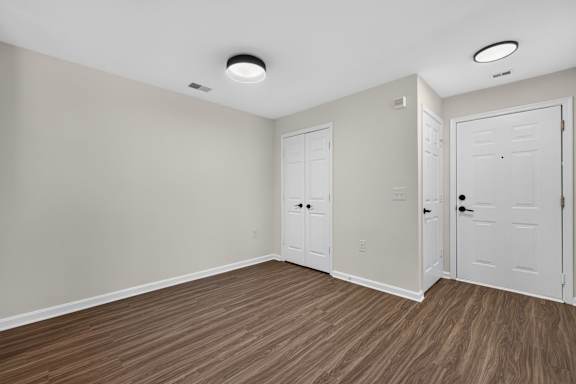 A room with white doors and brown flooring.