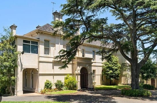 a large white house with a tree in front of it