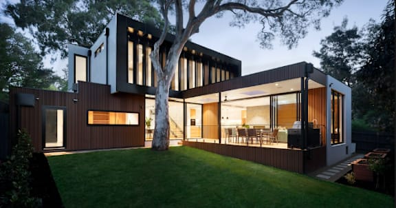 A modern house with a tree in front of it.