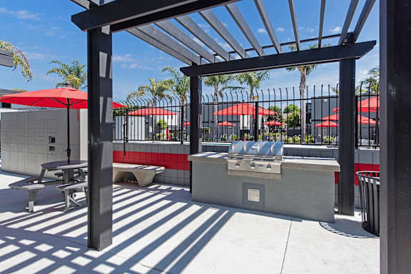 a patio with a grill and tables with umbrellas