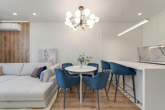 A modern dining area with a white table and blue chairs.
