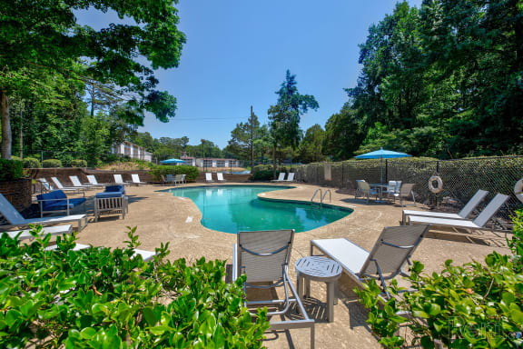 the pool is surrounded by chairs and umbrellas and trees