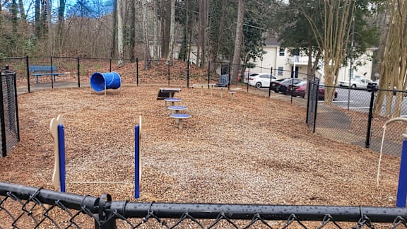 A playground with a blue barrel, a slide, and a bench.
