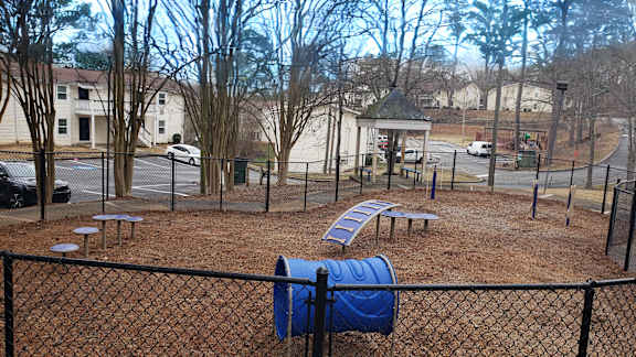 A playground with a blue slide and a black fence.