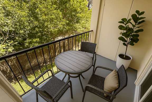 A patio with a round table and two chairs with a potted plant.