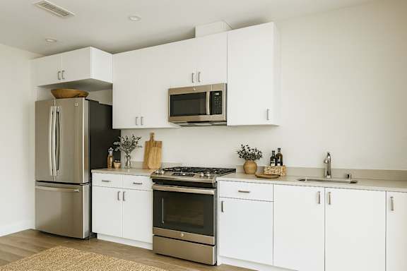A modern kitchen with white cabinets and stainless steel appliances.
