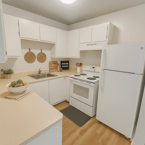 A white kitchen with a sink, stove, and refrigerator.