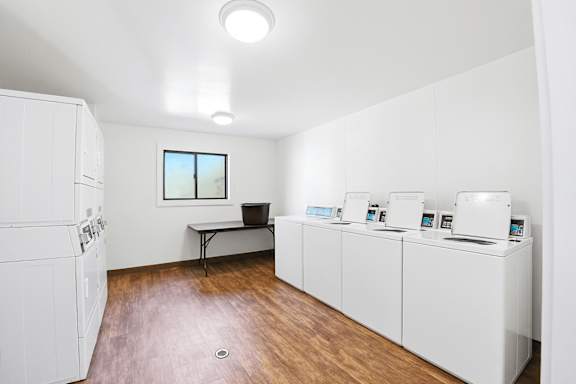 A room with white appliances and a table with a pot on it.