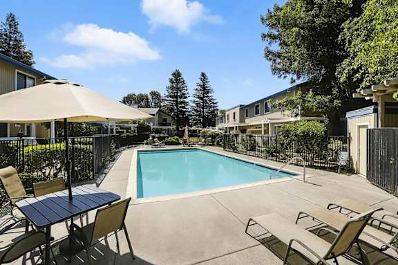 A pool surrounded by chairs and an umbrella.