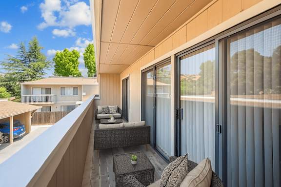 A balcony with a couch and a table with a green plant on it.