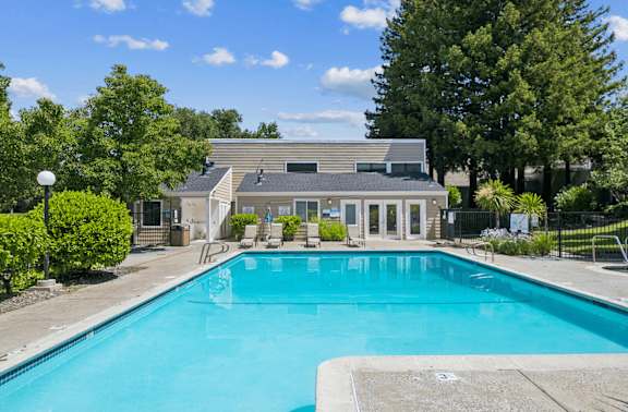 A swimming pool in front of a house surrounded by trees.