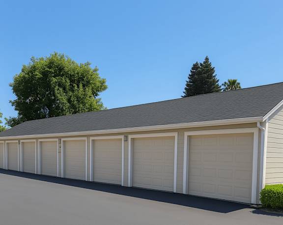 A long garage with white doors is situated in front of a house.