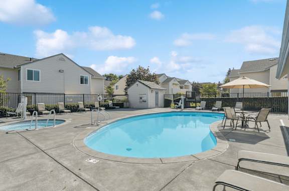 A swimming pool surrounded by lounge chairs and umbrellas in a residential area.