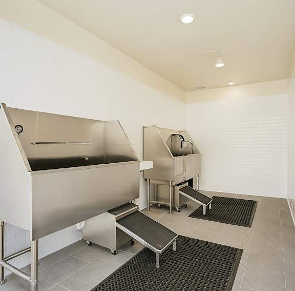 A clean, empty industrial kitchen with stainless steel appliances and black rubber mats on the floor.