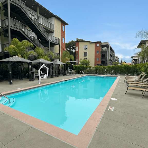 A large swimming pool surrounded by lounge chairs and umbrellas.
