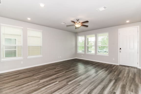 an empty bedroom with a ceiling fan and windows