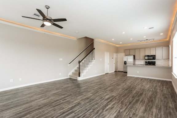 A spacious room with a staircase and a ceiling fan.