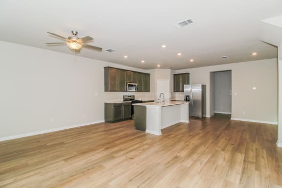 a kitchen and living room with hardwood floors and a ceiling fan