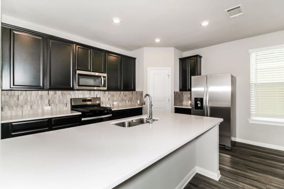 a kitchen with white countertops and black cabinets