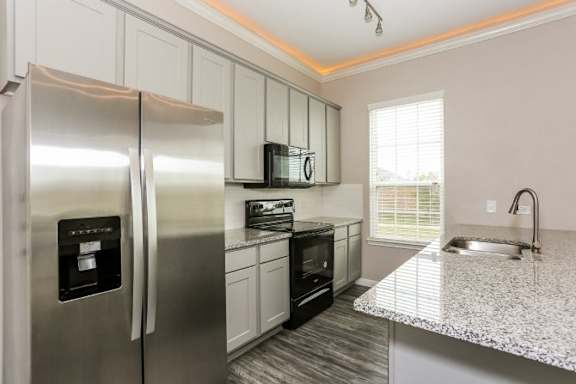 A modern kitchen with a stainless steel refrigerator and black oven.