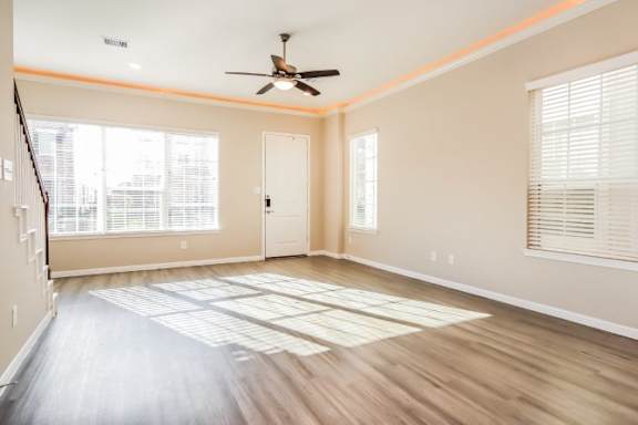 A room with a ceiling fan and wooden flooring.
