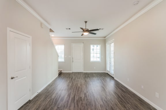 an empty living room with white walls and a ceiling fan
