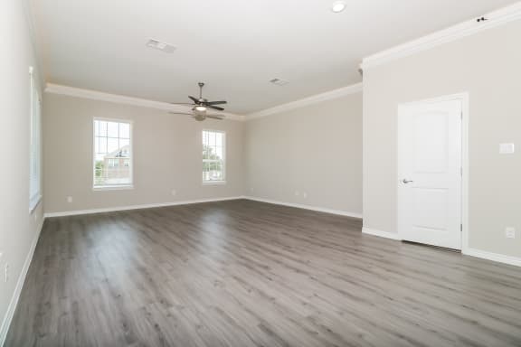 an empty living room with wooden floors and a ceiling fan