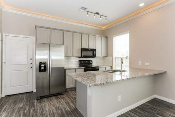 A kitchen with a granite countertop and stainless steel appliances.