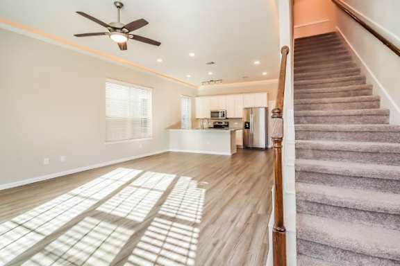 A room with a staircase and a ceiling fan.