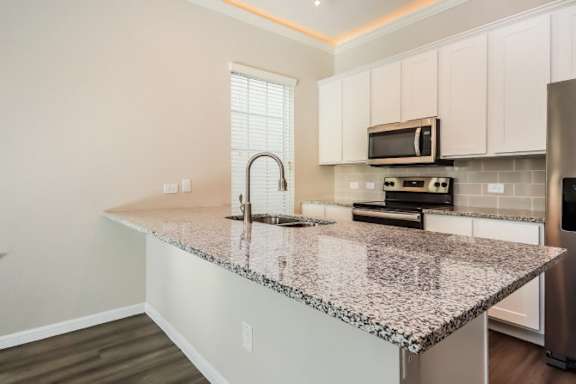 A kitchen with a granite countertop and white cabinets.