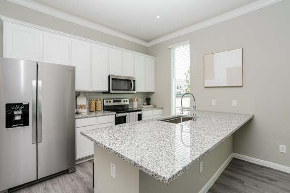 A kitchen with a granite countertop and stainless steel appliances.