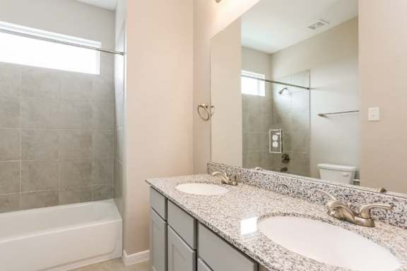A bathroom with a white tub and a granite countertop.