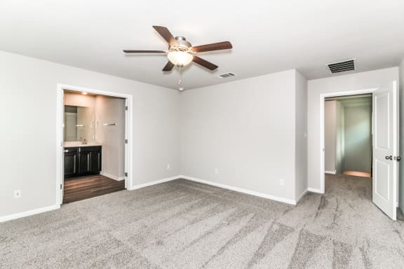 a bedroom with a ceiling fan and a doorway to a bathroom