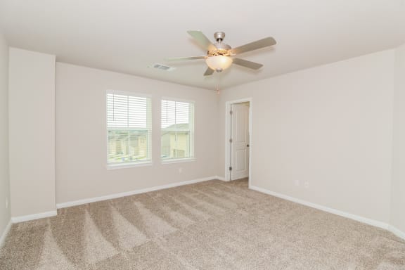 a bedroom with a ceiling fan and two windows