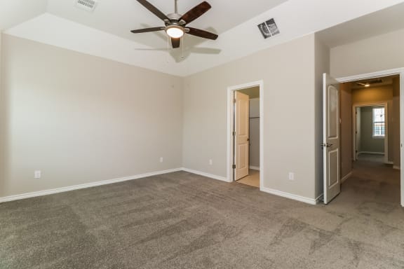 an empty living room with a ceiling fan and a hallway