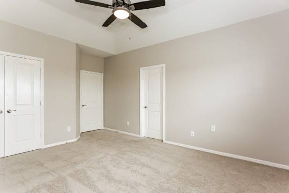 A room with a ceiling fan and carpeted floor.