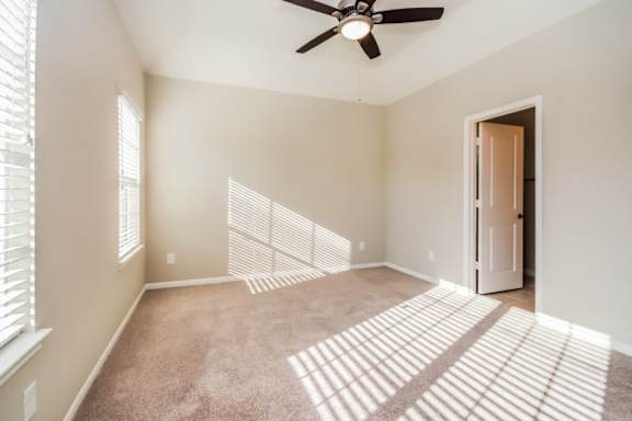 A room with a ceiling fan and a carpeted floor.